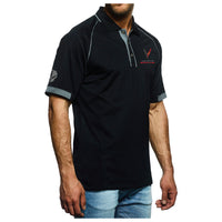 A man wearing a black short-sleeve polo shirt with gray trim and a red and white logo on the left chest, paired with light blue jeans, against a plain white background.
